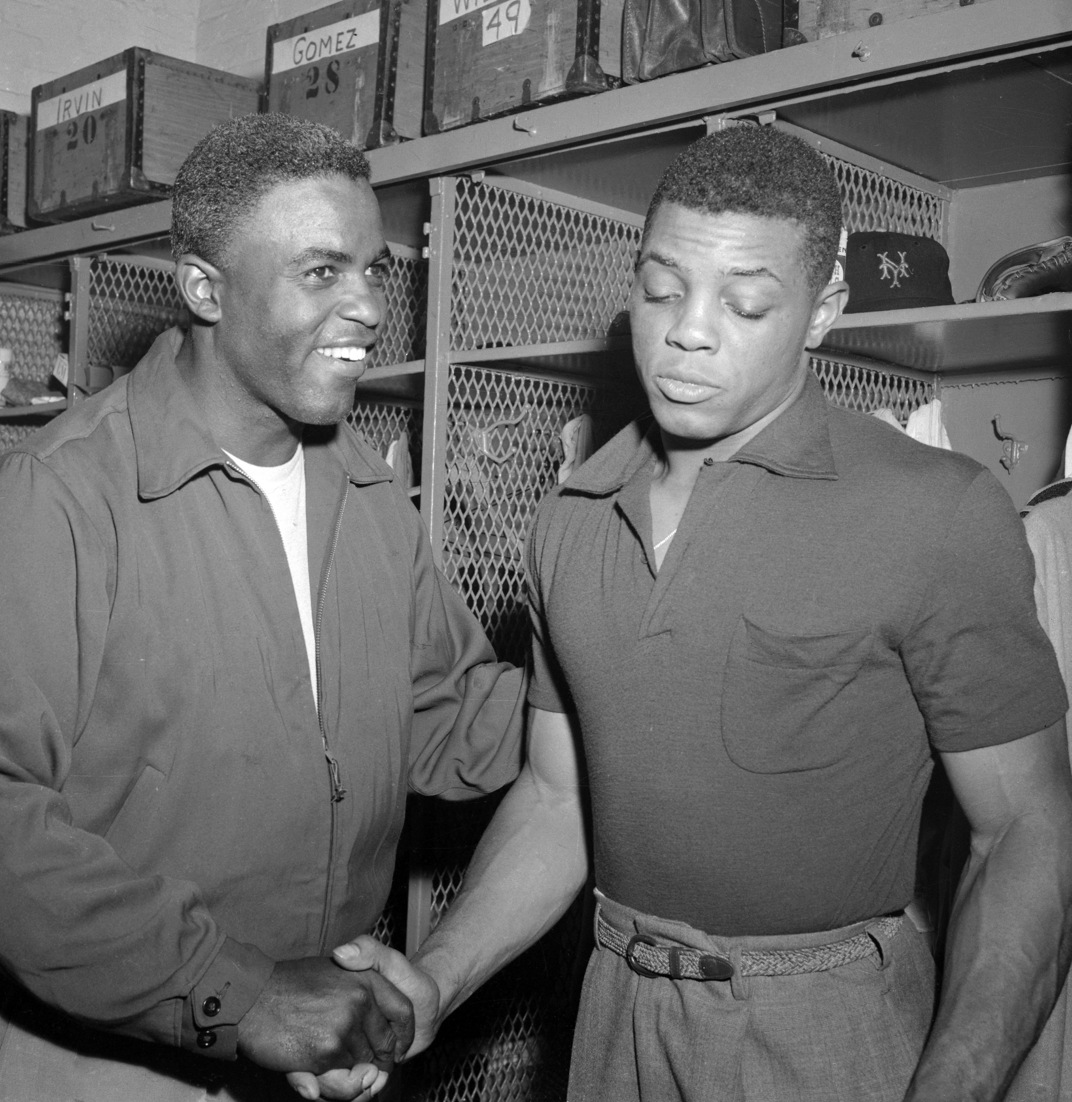 Jackie Robinson of the Brooklyn Dodgers (L) congratulates New York Giant Willie Mays, after the Giants beat the Dodgers 7 to 1, capturing the 1954 National League pennant.